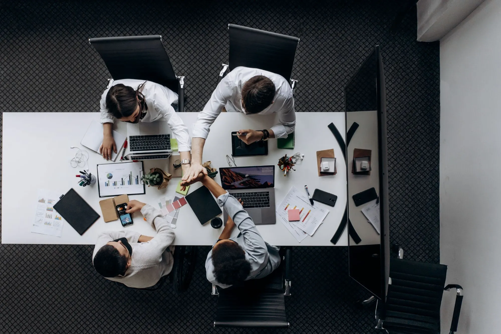 A team around a shared desk giving each other a high five